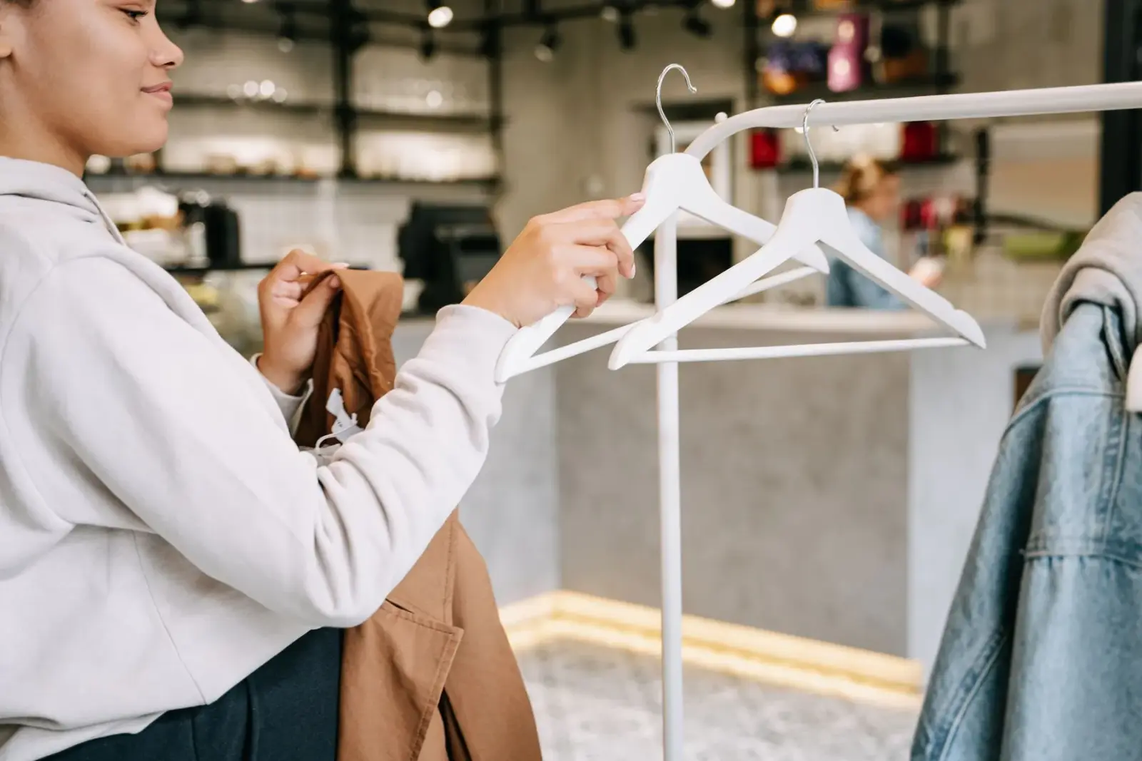 Người phụ nữ chọn đồ giữa các giá treo trong cửa hàng hiện đại