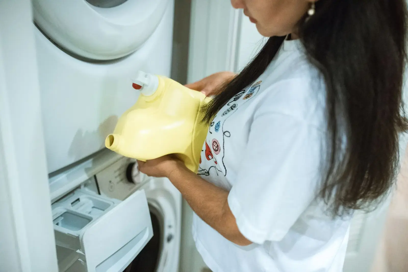 Người phụ nữ rót nước giặt vào ngăn của máy giặt