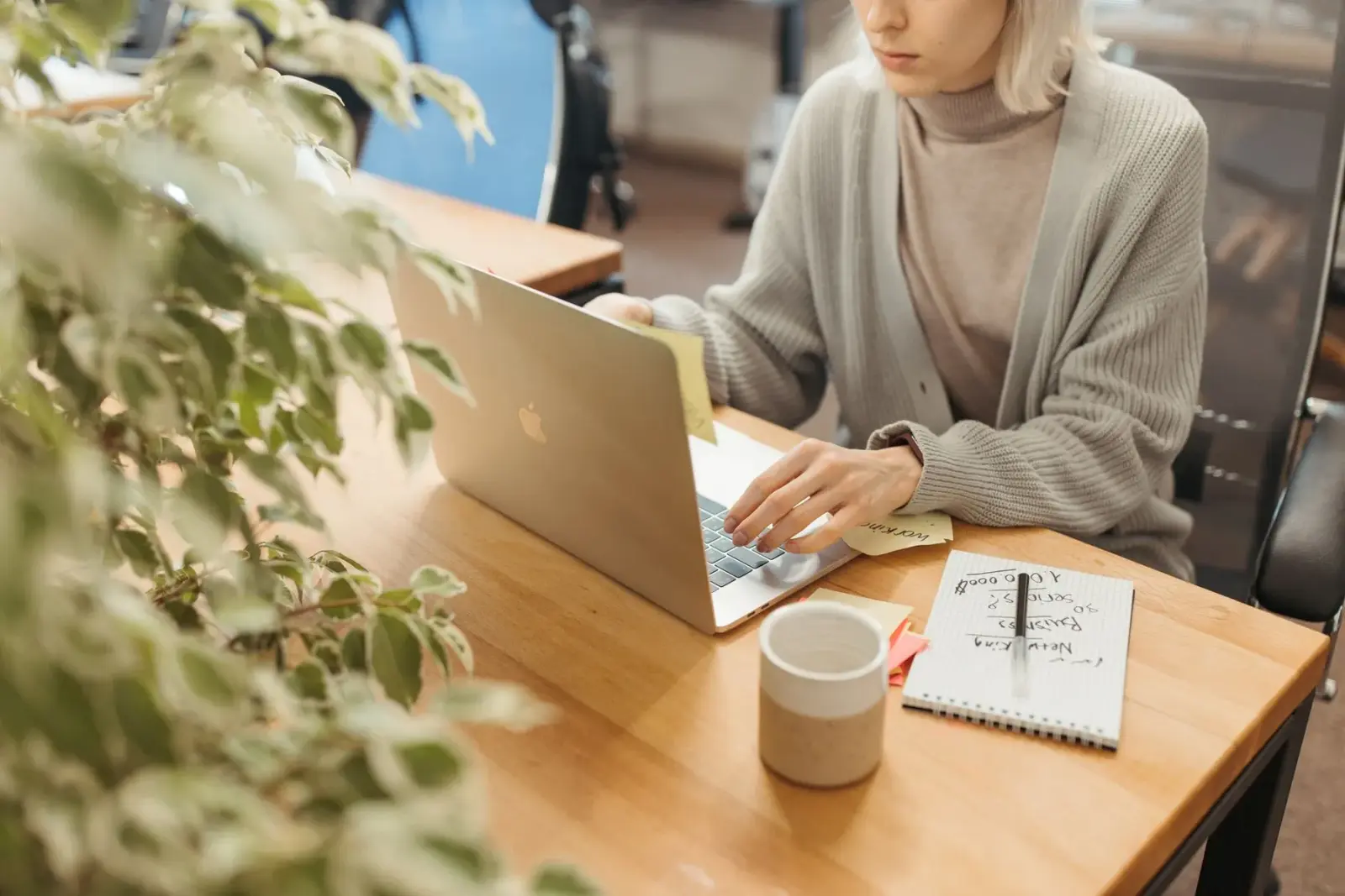Người phụ nữ làm việc với máy tính xách tay trên bàn gỗ